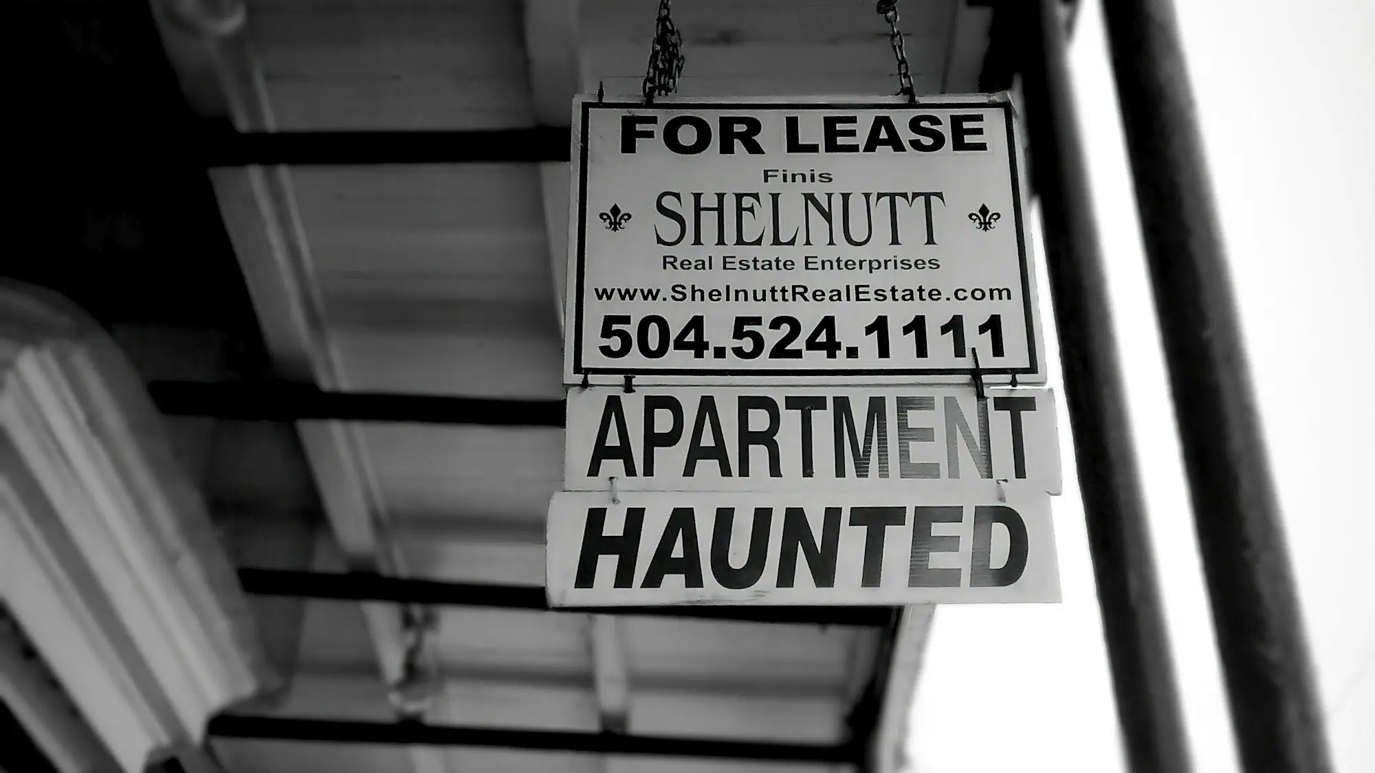 Business sign hanging from the side of a building on a city street