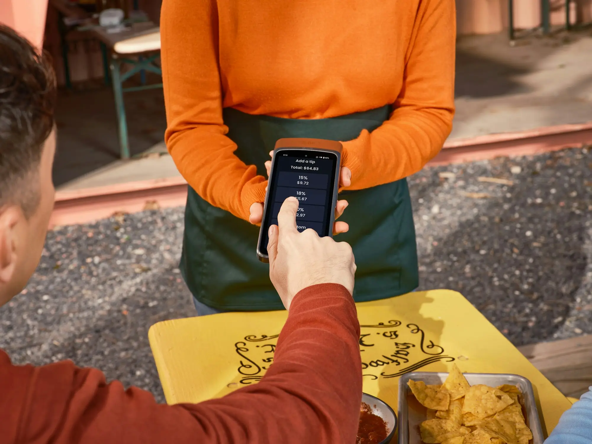 Customer paying with a smartphone at an outdoor cafe table