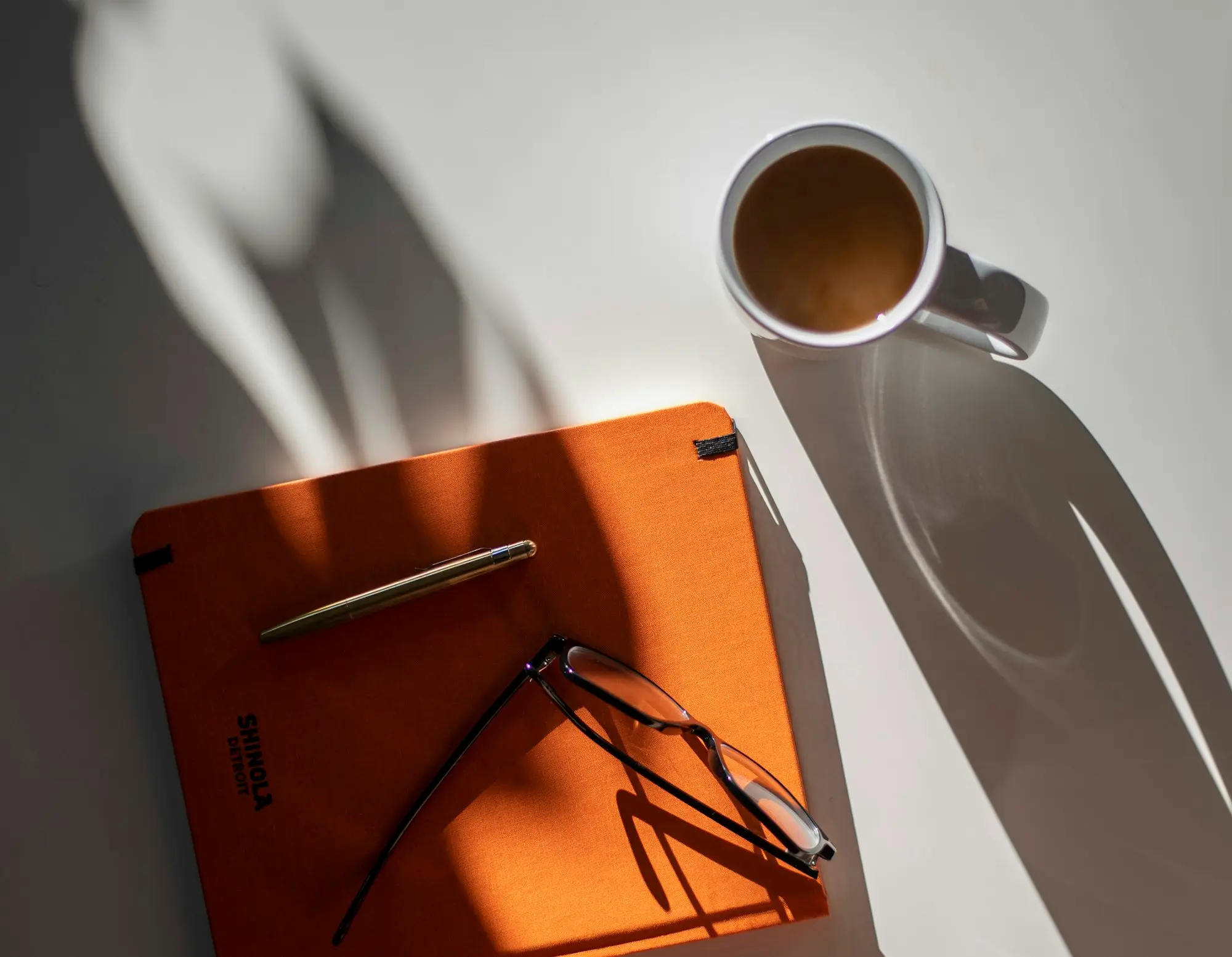 Reading glasses lying on an orange book on a desk
