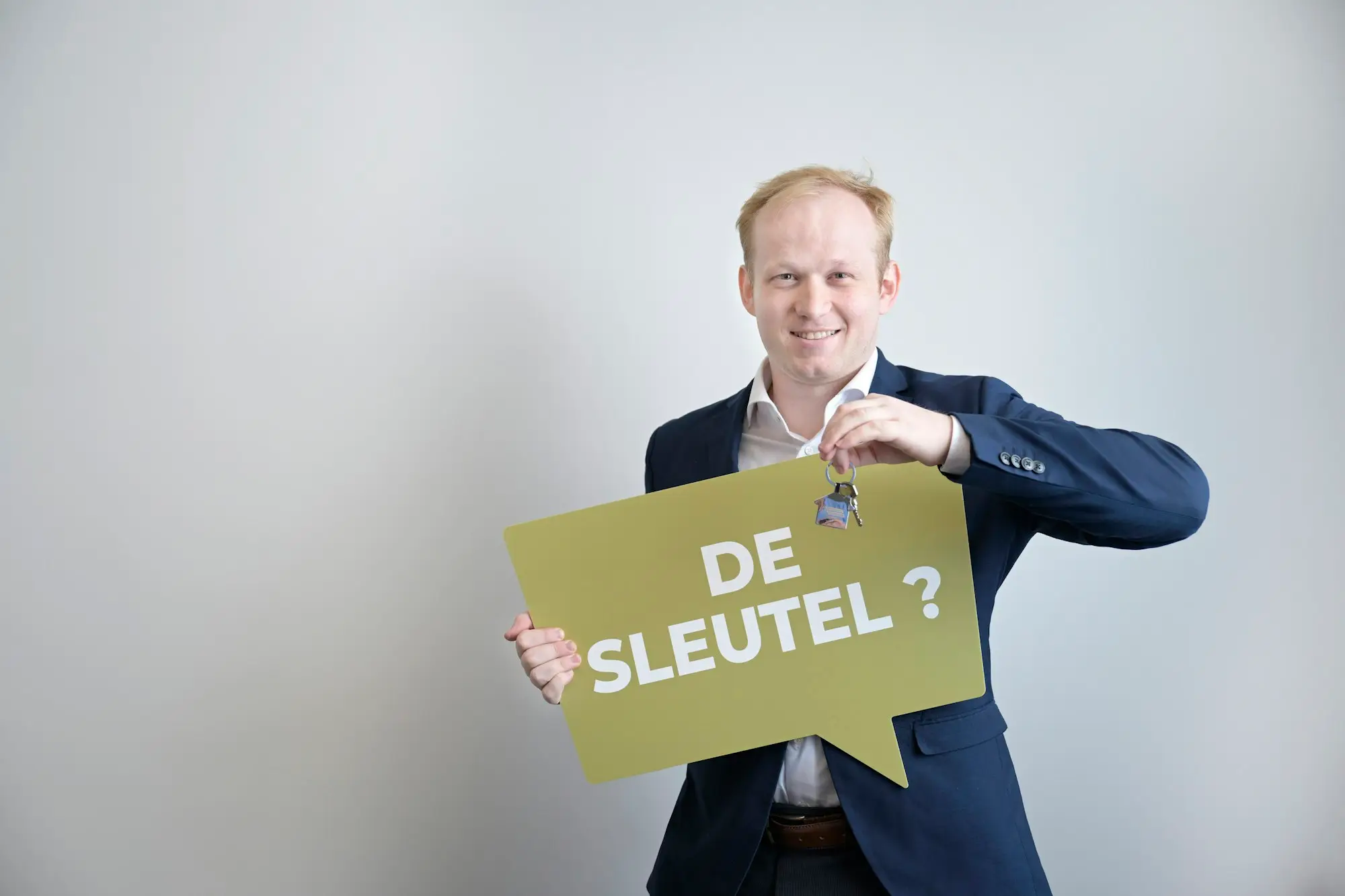 Man in a suit holding up a set of house keys